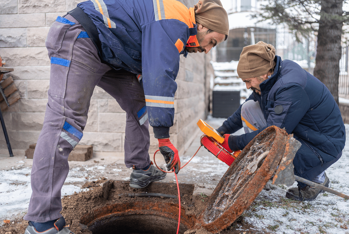 Workers inspecting open manhole cover