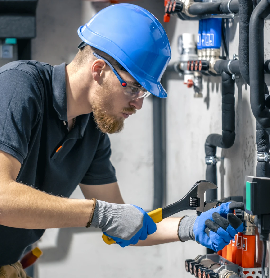 Worker with wrench adjusting industrial pipes