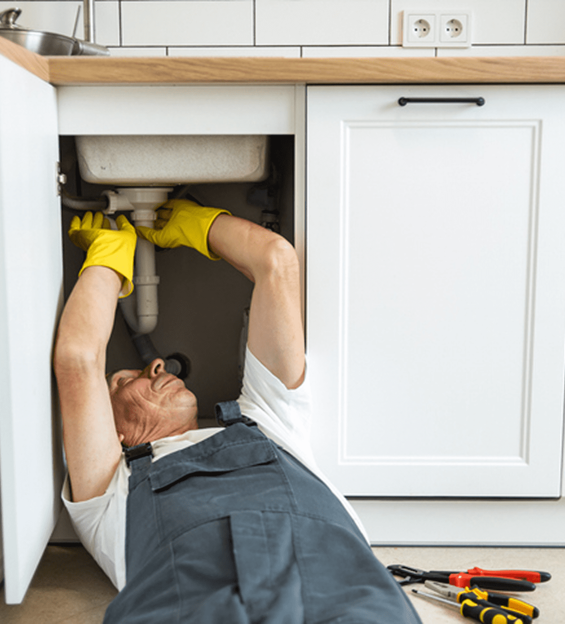 Man in overalls repairing plumbing