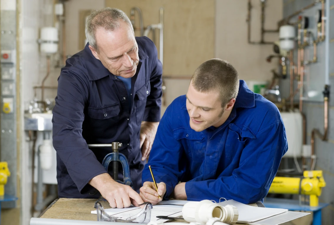 Workers discussing plans at workbench