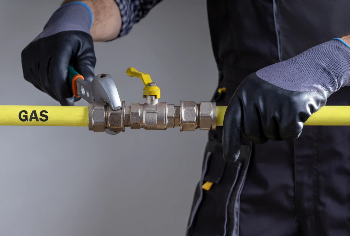 Worker adjusting gas pipe with wrench