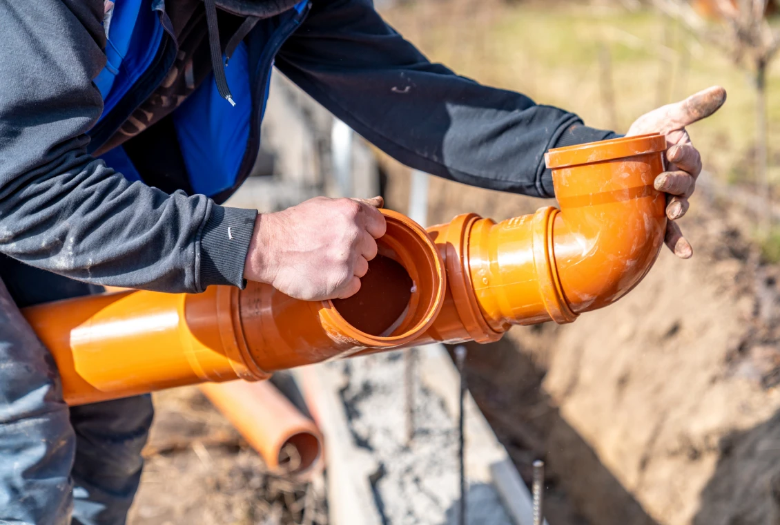 Hands connecting sewer pipe sections outdoors