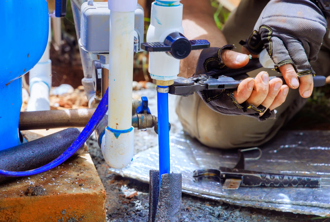 Worker repairing blue water pipe outdoors