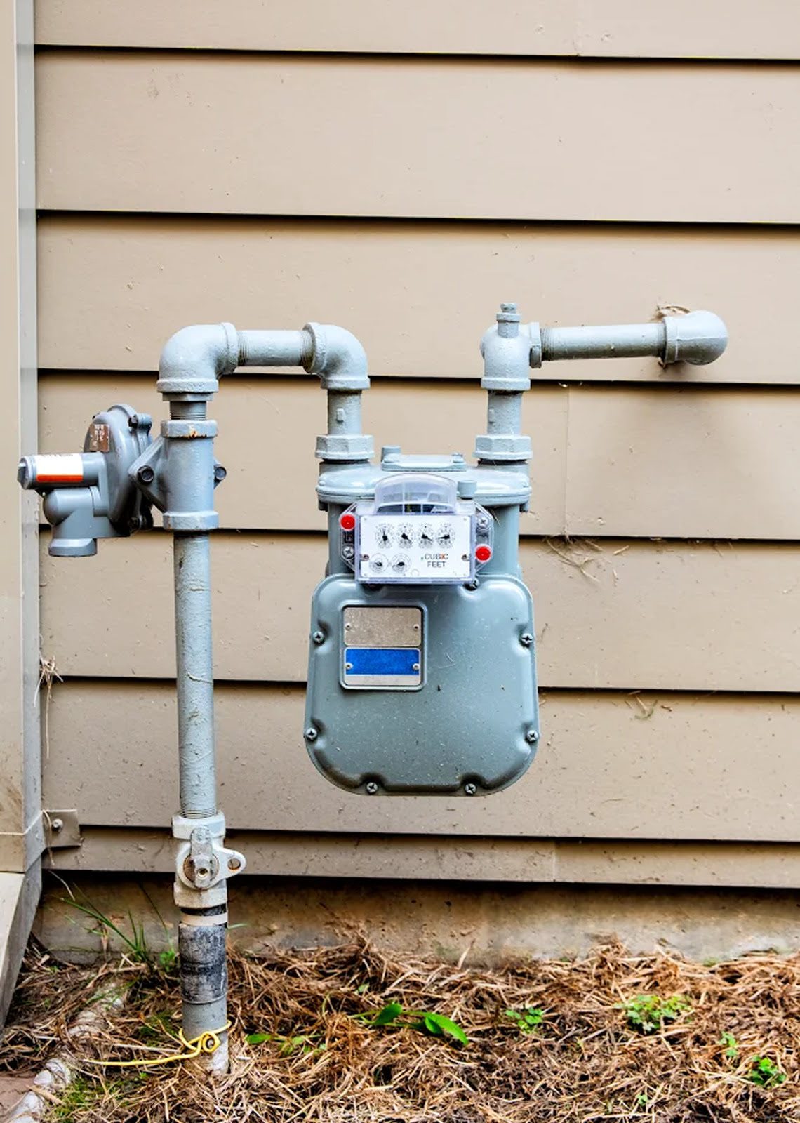 Gas meter attached to house exterior wall.