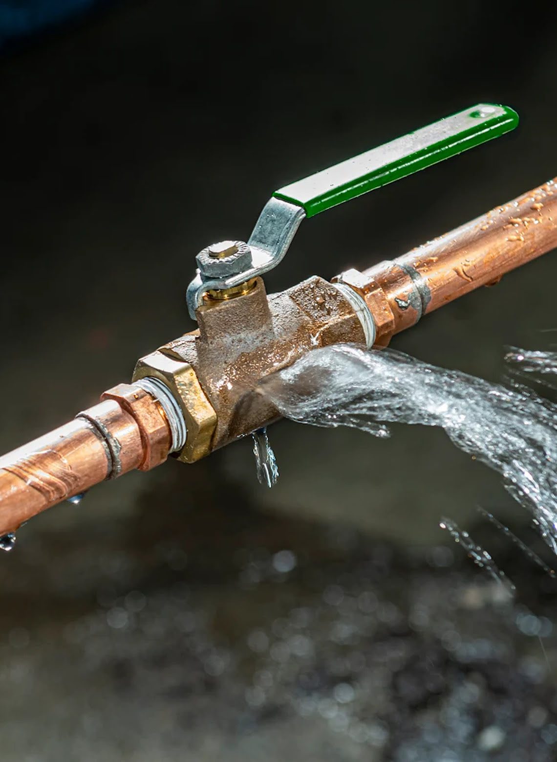 Leaking copper pipe with green-handled valve.